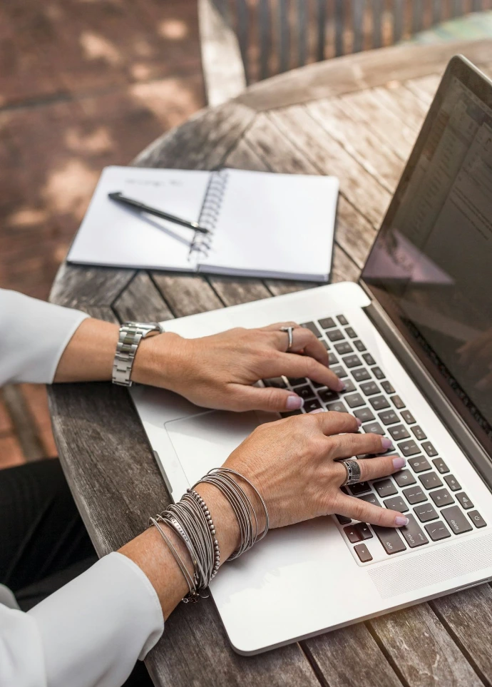 person typing on MacBook Pro on brown wooden table during daytime photo